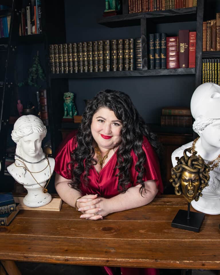 Kara Loewentheil leaning on a table inbetween various sculptures.